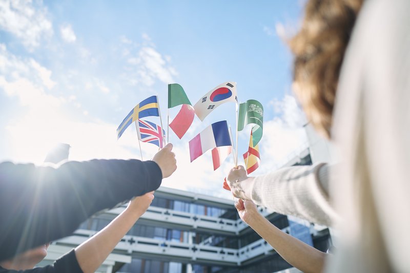 Vier Personen halten verschiedene Länderflaggen in die Luft