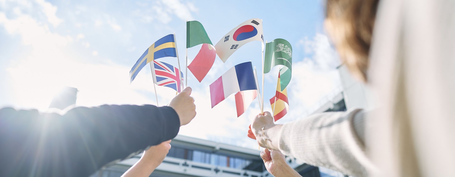 Vier Personen halten verschiedene Länderflaggen in die Luft